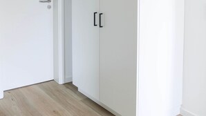 A white wardrobe with two doors and a handle, positioned next to a white door with a silver handle.