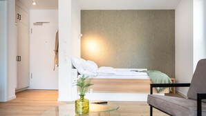 A modern bedroom with a bed, a bedside table with a vase, a chair, and a glass table. - Osternburg (Oldenburg)