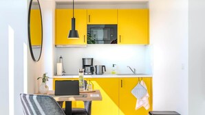A modern kitchen with yellow cabinets, a microwave, a coffee maker, and a laptop on the counter. - Eversten- Penthouse (Oldenburg)