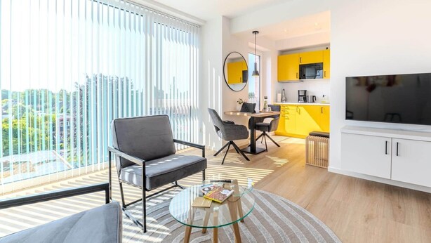 A modern apartment with a dining area, kitchen, and a balcony with large windows. - Eversten- Penthouse (Oldenburg)