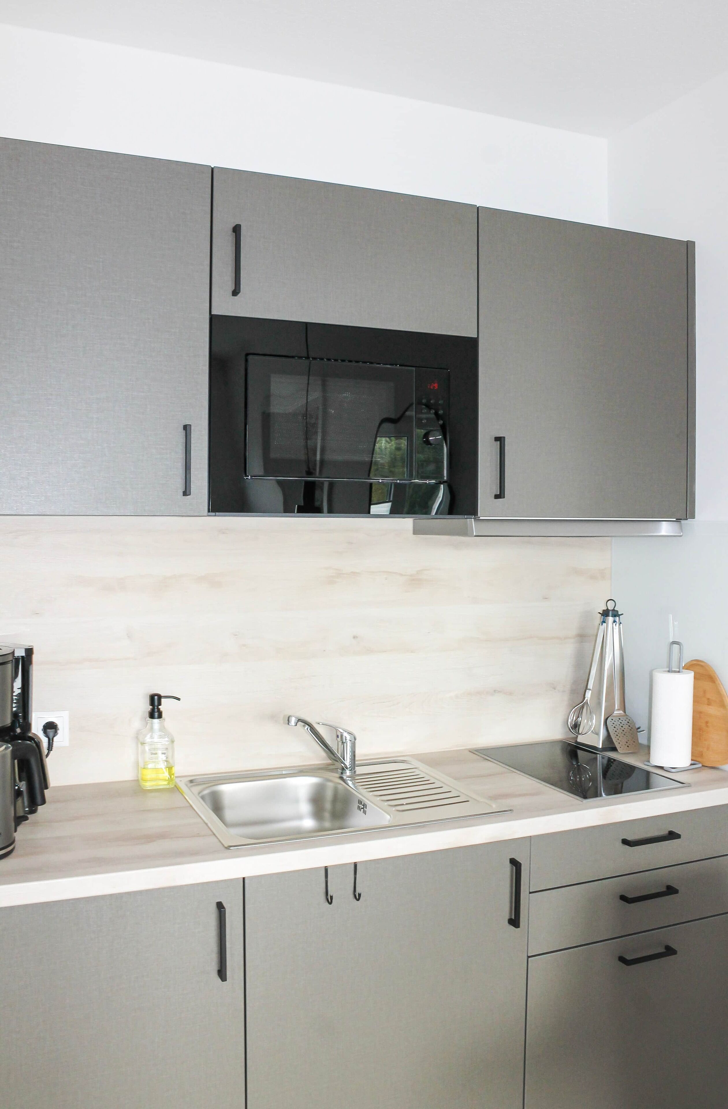 A modern kitchen with stainless steel cabinets, a double sink, and a microwave.