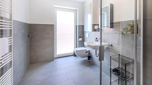 A modern bathroom with a glass shower enclosure, a toilet, and a sink. - Kreyenbrück (Oldenburg)