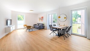 A spacious living area with a dining table, sofas, and a TV. - Kreyenbrück (Oldenburg)