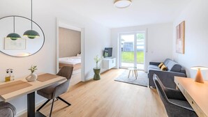 Una habitación moderna y bien iluminada con una cama, un escritorio, un sofá y un televisor.