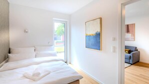 Un dormitorio moderno con una cama grande, un cuadro en la pared y vistas al exterior.
