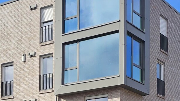 Un edificio moderno de varios pisos con grandes ventanales y techo plano.