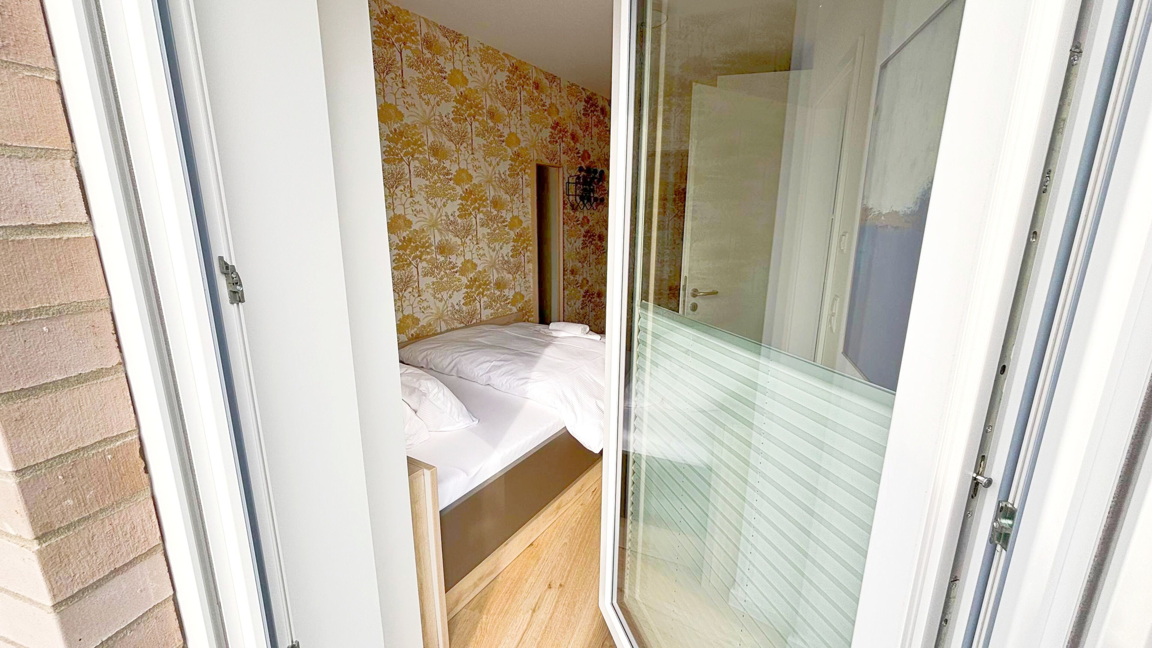 A bedroom with a bed, a window, and a door.