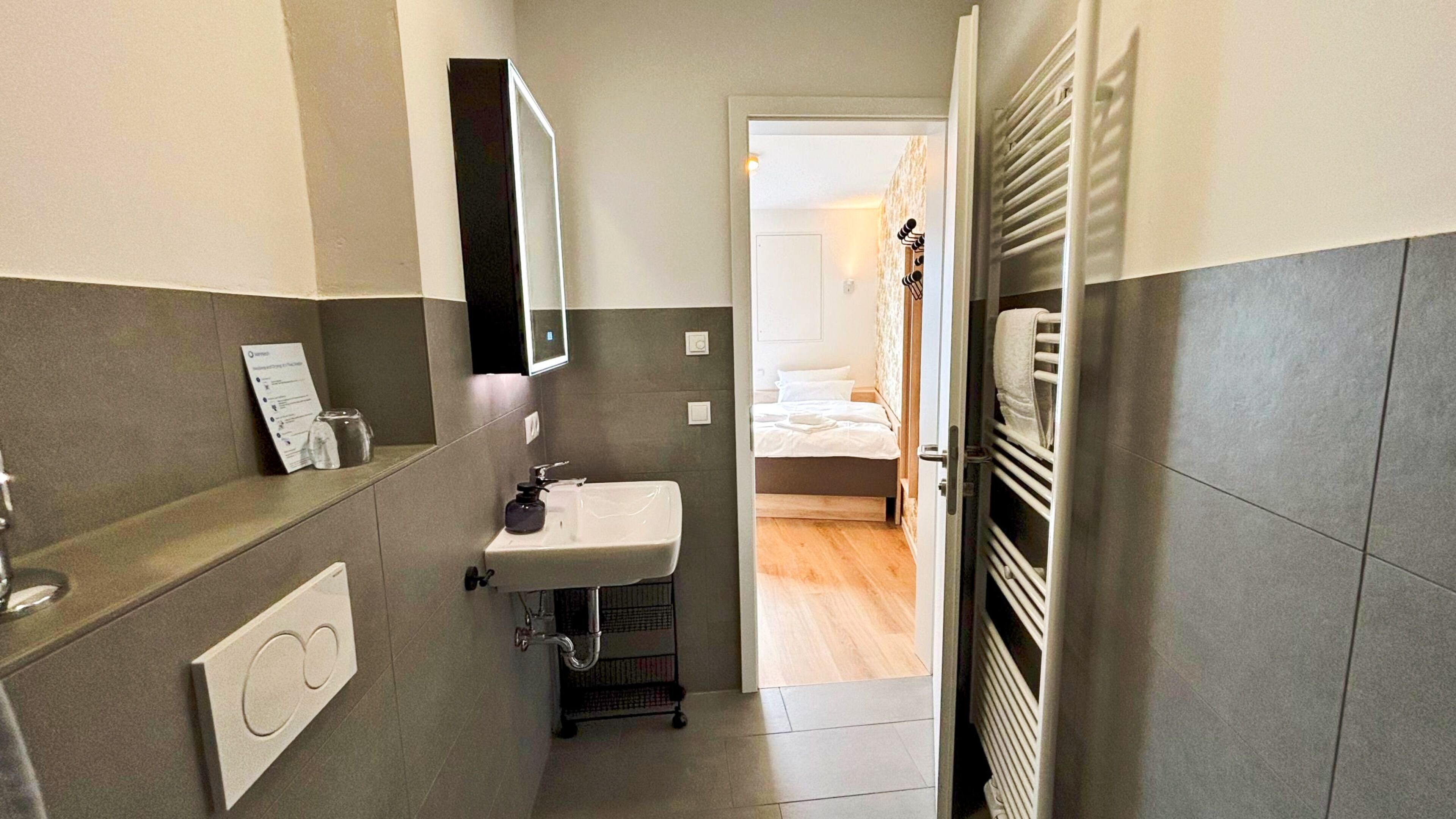 A compact bathroom with a sink, mirror, and towel rack.