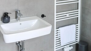 A bathroom with a white sink, a mirror, and a towel rack.