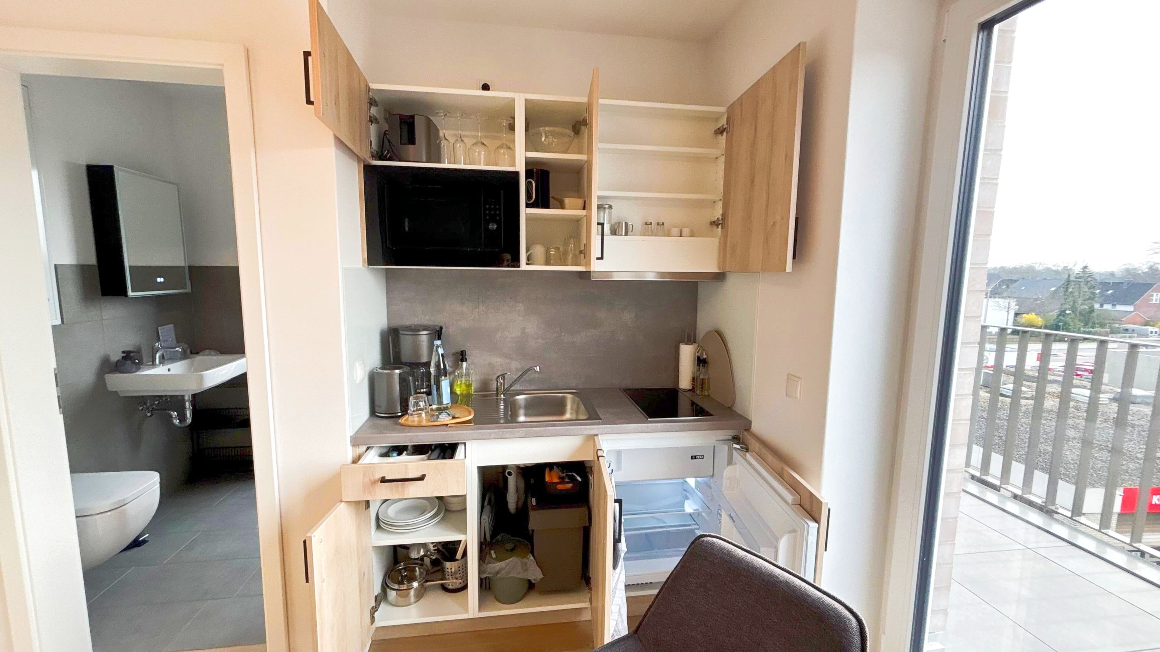 Une cuisine compacte équipée d’un évier, d’un four à micro-ondes et de placards de rangement.
