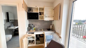 Une cuisine compacte équipée d’un évier, d’un four à micro-ondes et de placards de rangement.
