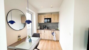 A modern kitchen with wooden cabinets, a dining table, and a large mirror. - Drielake (Oldenburg)