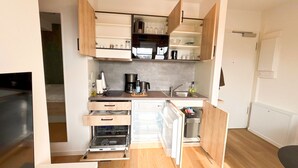 A compact kitchen with wooden cabinets, a built-in oven, a dishwasher, and a sink.