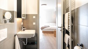 Un baño moderno con lavamanos, espejo y toallero.