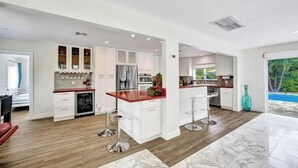 Una cocina moderna con armarios blancos, encimera roja y una isla central con taburetes de bar.