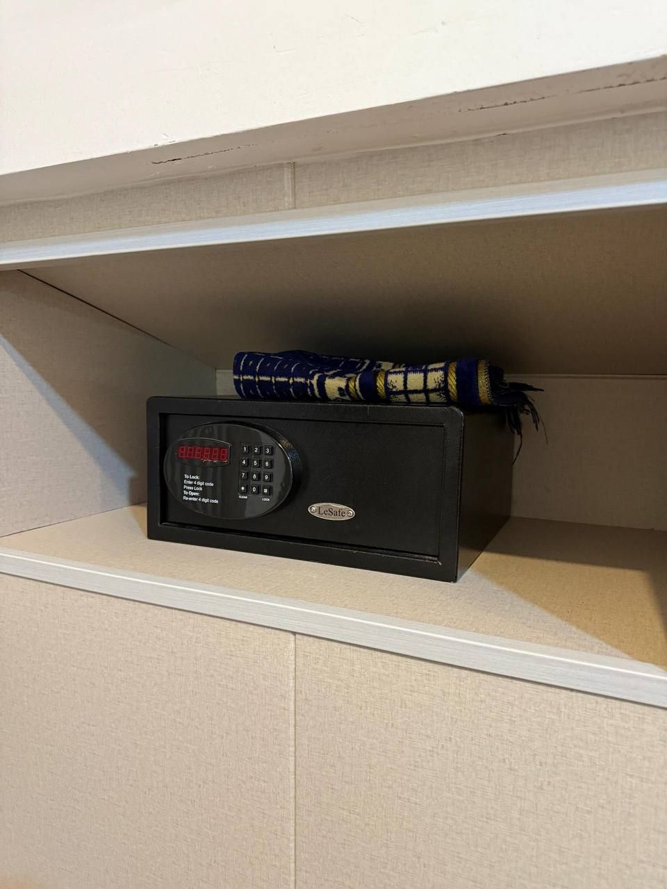 Un coffre-fort LeSafe posé sur une étagère, avec un objet aux motifs bleus et jaunes placé sur le dessus.
