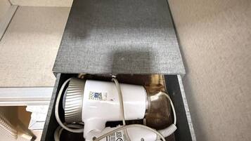 A white portable heater with a power cord and a plug inside a black box.