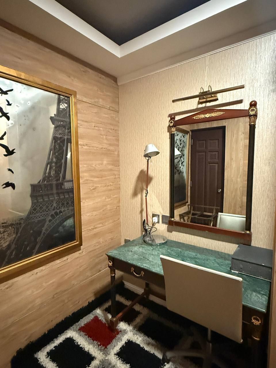 A room with a desk, chair, and a large mirror.