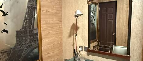 A room with a desk, chair, and a large mirror.