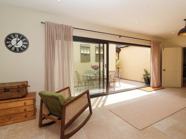 A room with a sliding glass door leading to an outdoor area, a wooden dresser, a rocking chair, and a wall clock.