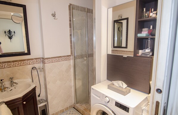 Bagno con lavandino, specchio, doccia e lavatrice.
