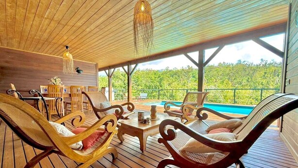 A wooden deck with wicker chairs and a table, overlooking a swimming pool. - Villa Letchis, Authenticity & Calm (Saint-Benoît)