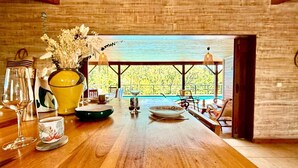 A wooden dining table with a view of a pool and trees. - Villa Letchis, Authenticity & Calm (Saint-Benoît)