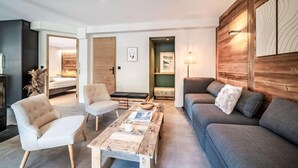 Een moderne woonkamer met een bank, twee fauteuils, een salontafel en een houten accentmuur.