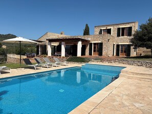 A poolside area with lounge chairs and a stone pool. - Fetget, quiet rural property with swimming pool. (IB)