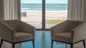 A room with two armchairs facing a large sliding glass door leading to a beach view. - Villa Preziosa Front Beach (Fleicheiras)
