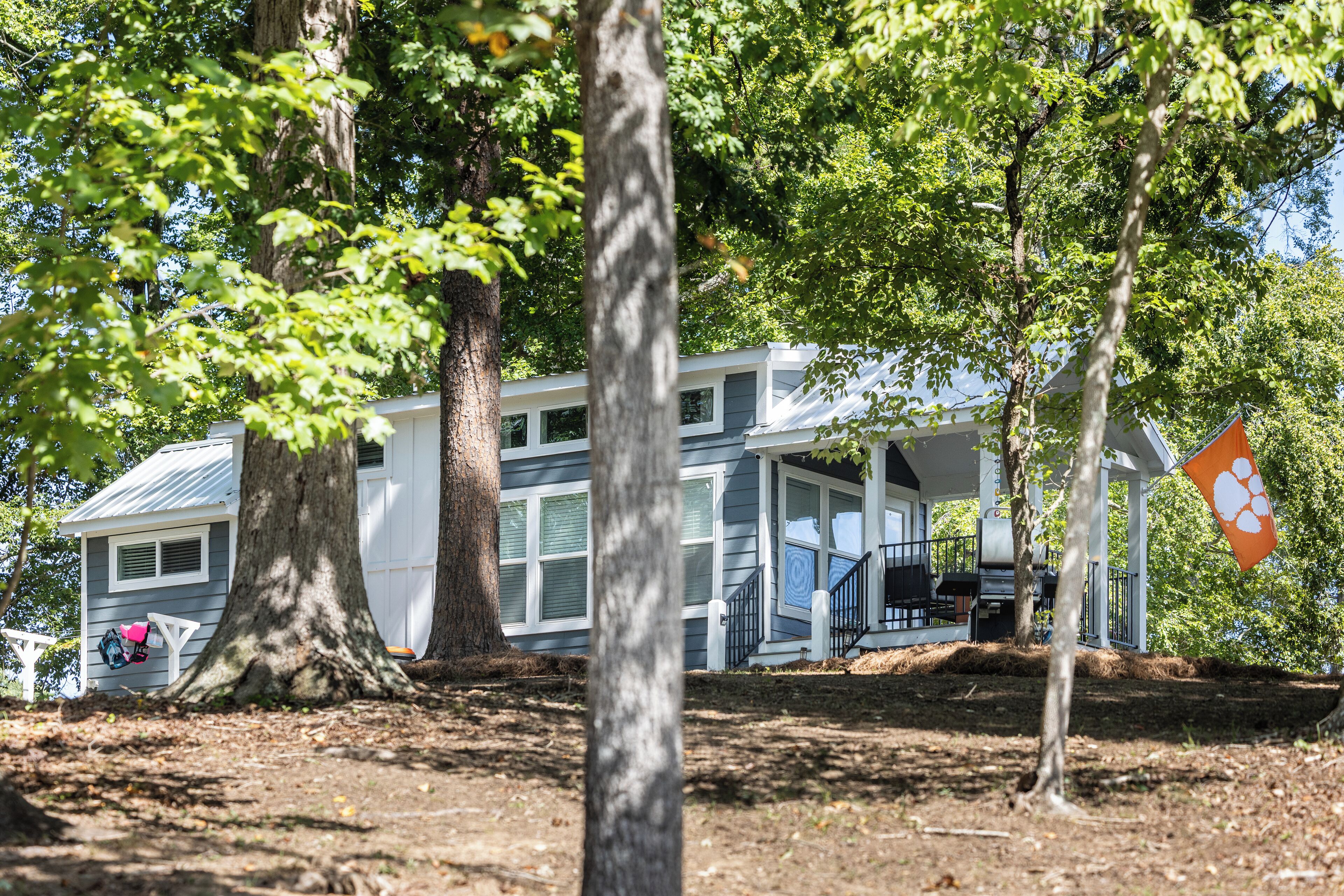 A modern house with a covered porch, large windows, and a tree in the foreground.