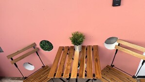 A wooden table with a potted plant in the center, flanked by two chairs with circular cutouts. - Cityscape Escape/Art District Vibes/Bay & City Views (San Juan)