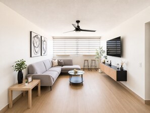 A modern living room with a sofa, coffee table, and a TV mounted on the wall.
