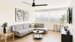 A modern living room with a grey sofa, a round coffee table, and a ceiling fan. - Cityscape Escape/Art District Vibes/Bay & City Views (San Juan)