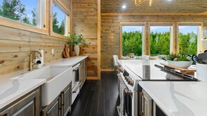 Une cuisine moderne avec des murs en bois, de grandes fenêtres et un îlot central.