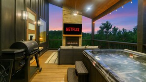 Une terrasse extérieure avec un foyer, un jacuzzi et un espace barbecue.