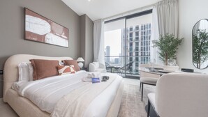 Et moderne hotelværelse med en stor seng, et spiseområde og en balkon med udsigt over byen.