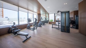 Et moderne fitnesscenter med forskellig træningsudstyr, store vinduer og udsigt over bybilledet.