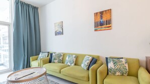 Ein Wohnzimmer mit einem grünen Sofa, einem runden Couchtisch und zwei Wandbildern.