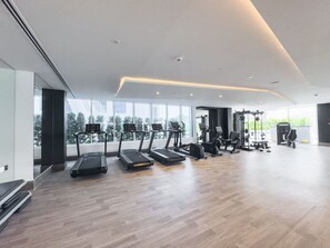 Et moderne fitnesscenter med løbebånd, styrkemaskiner og et stort vindue med udsigt over byen.