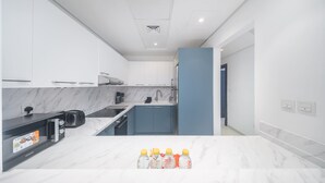 Cocina moderna con armarios blancos, encimera de mármol y una pared azul de acento.