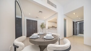 Un comedor moderno con una mesa redonda para cuatro personas, rodeada de sillas cómodas, y un espejo grande en la pared.