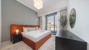 Un dormitorio moderno con una cama grande, una mesita de noche, un aparador y vistas a la ciudad a través de amplias ventanas.