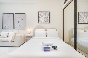 A hotel room with a bed, a nightstand, a lamp, and two wall art pieces. - Business Bay Studio With Private Jacuzzi (Dubai)