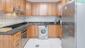 Een moderne keuken met houten kastjes, een ingebouwde wasmachine, een koelkast en een magnetron.