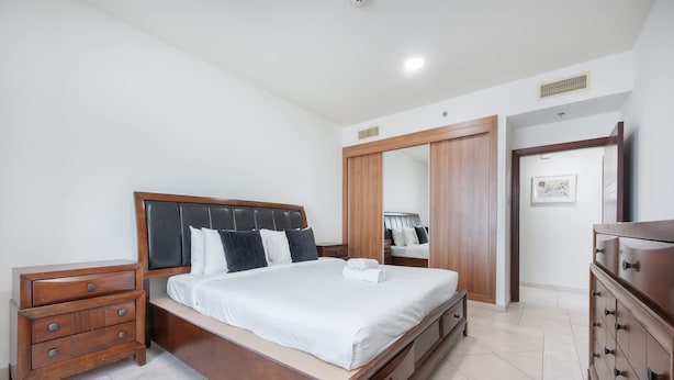 Een slaapkamer met een houten bed, nachtkastje, dressoir en garderobekast.