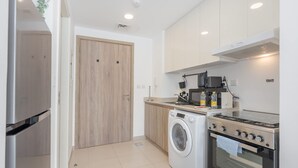 Une cuisine moderne équipée d’un lave-linge, d’une cuisinière, d’un four à micro-ondes et de meubles de rangement en bois.