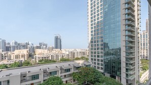 Un edificio de gran altura con fachada de vidrio, rodeado de otros edificios residenciales y vegetación.