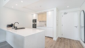 Una cocina moderna con armarios blancos, una isla central y electrodomésticos integrados.