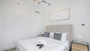 Una habitación de hotel moderna con una cama grande, una mesita de noche con lámpara y una decoración minimalista.